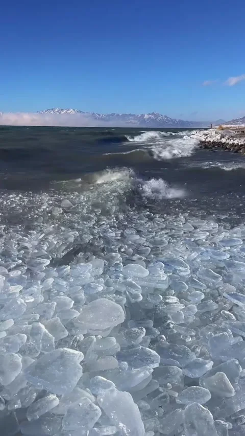 Vertical video of big blue waves crashing violently onto frozen ice shards o Stock Footage 327693975