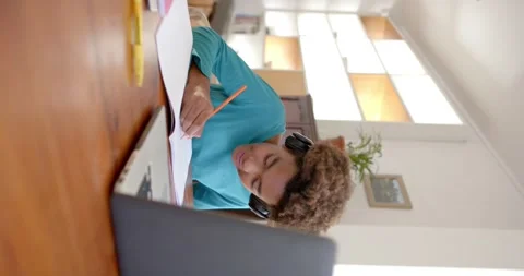 Vertical video of biracial boy using laptop for online class, slow motion Stock Footage 245891439