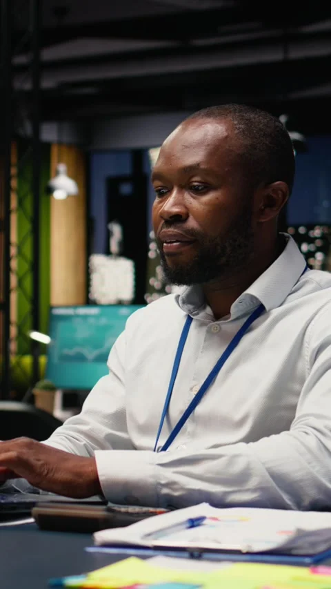 Vertical Video Black man accountant in office using laptop and writing down Stock Footage 334104010