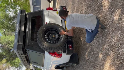 Vertical video. Black man repairing car, change spare tire at SUV vehicle. 動画素材 168907053