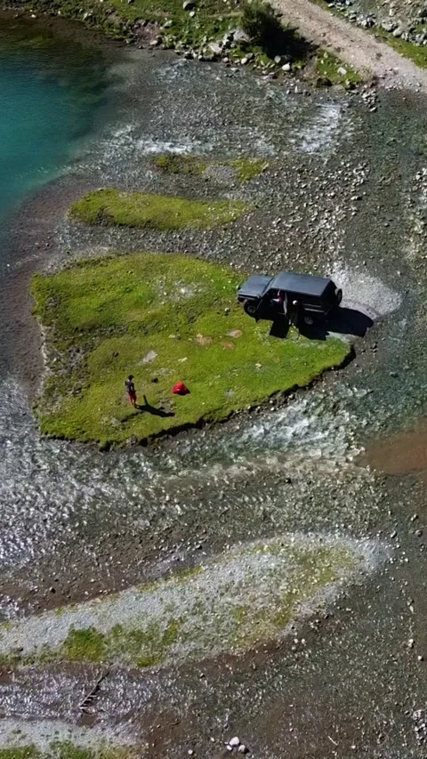 Vertical video: Black SUV and Base Camp on Green Island by Turquoise Lake Stock Footage 332010535