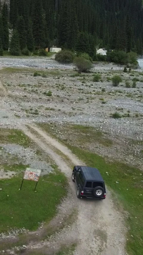 Vertical video: Black SUV Driving Past Road Sign into Mountain Wilderness Video stock 332010382