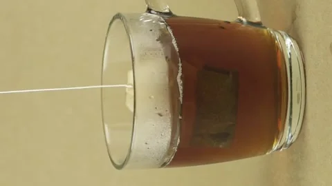 Vertical video black tea bag lifting and dropping into glass transparent mug to Stock Footage 151997795