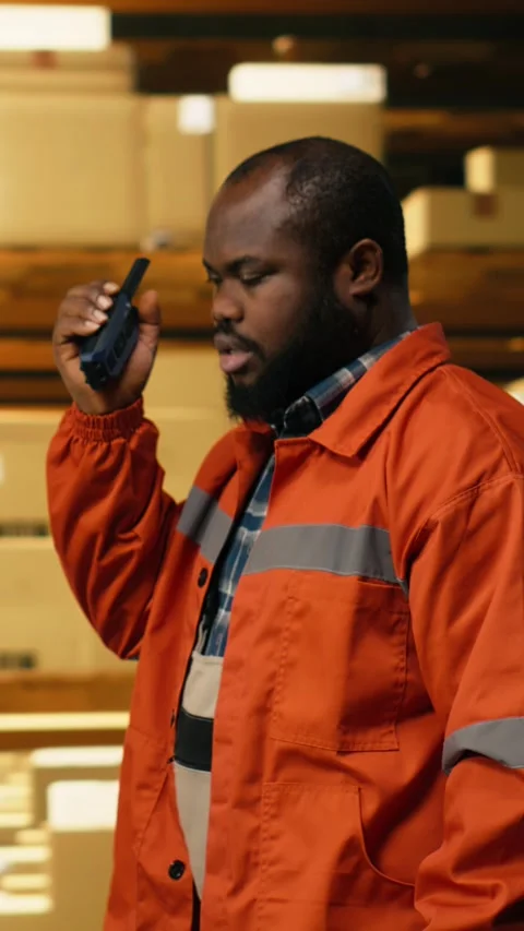 Vertical Video Black warehouse operator using portable walkie-talkie radio in Stock Footage 333089579