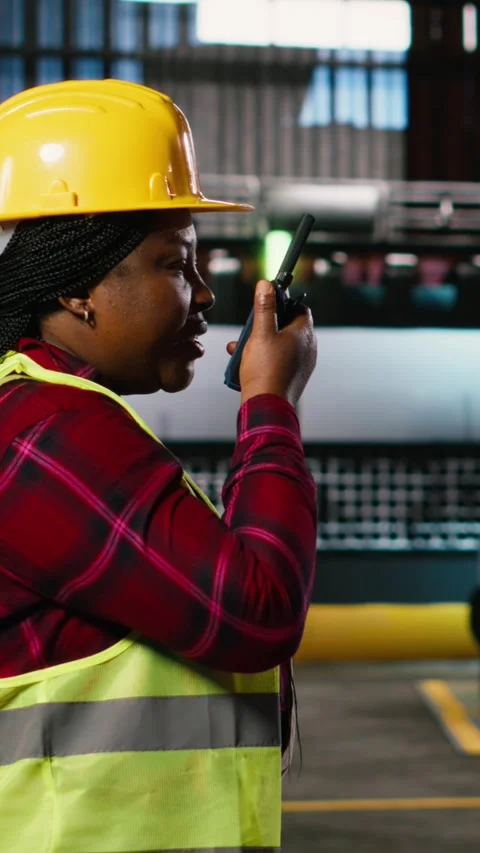 Vertical Video Black woman engineer speaking into portable walkie-talkie device Stock Footage 330138852