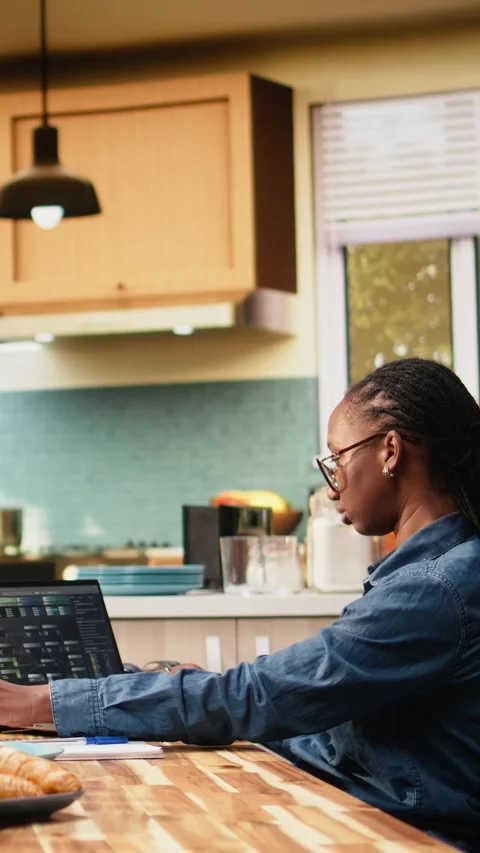 Vertical Video Black woman programming on laptop in kitchen representing hybrid Vídeo Stock 344529549