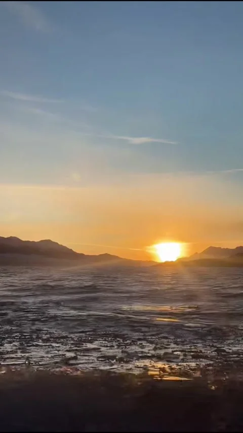 Vertical Video of Blue Ice Waves and Sunrise over Mountains at Sayram Lake Stock Footage 328389456