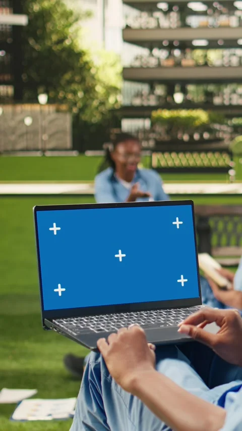 Vertical Video Blue screen mockup on laptop held by seated student in scrubs on Stock Footage 341321412