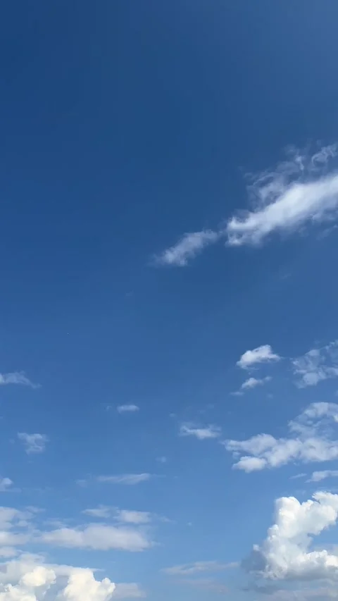 Vertical video of a blue sky with white clouds drifting Stock Footage 308926071