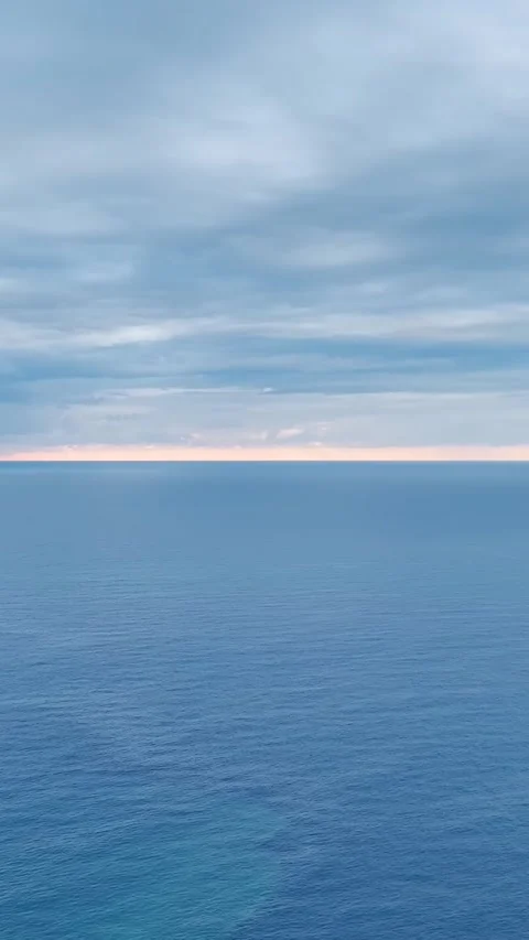 Vertical Video: Blue tones of a sunset reflecting on the sea, showcasing the Stock Footage 297637894