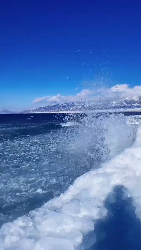 Vertical video of blue waves crashing against ice shelf creating splashes at Stock Footage 327689727
