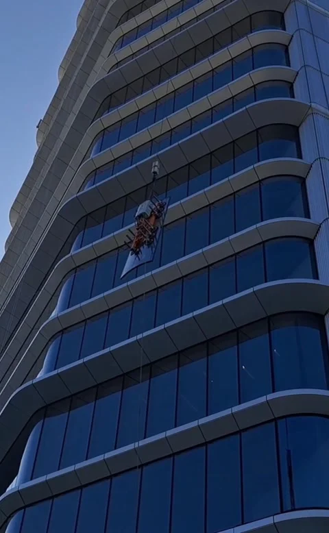 Vertical video of BMU crane hoisting glass pane to skyscraper roof Stock Footage 337359388