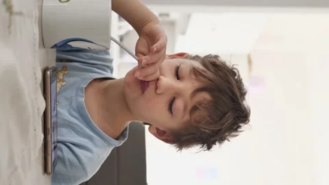 Vertical video. boy eats breakfast and looks at the phone Stock Footage 154200098