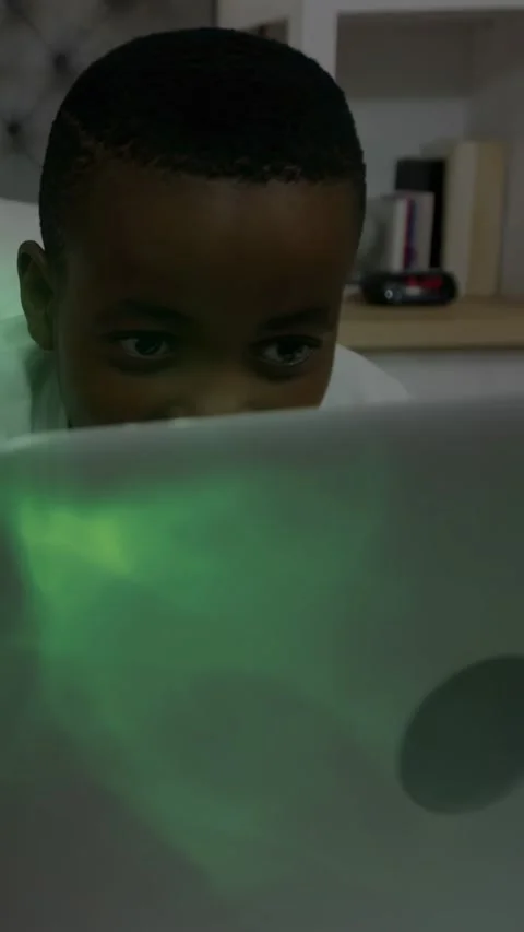 Vertical video: Boy leaning on laptop, green glow pulling him in, shifting into Stock Footage 329961519