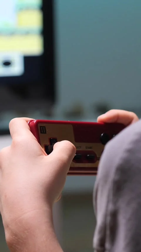 Vertical video Boy playing retro video games at home using controller Video stock 302657435