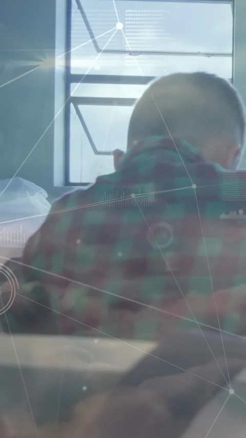 Vertical video: Boy sitting at table by window, software overlaying HUD, marking Stock Footage 331270914