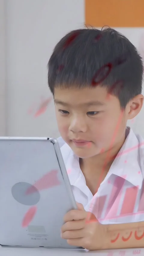 Vertical video: Boy tapping tablet in class, pink charts over screen as teacher Stockbeeldmateriaal 333182114