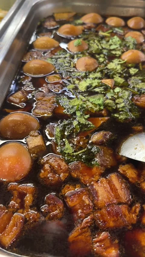 Vertical video of braised eggs and pork belly simmering in dark soy broth Stock Footage 321182398