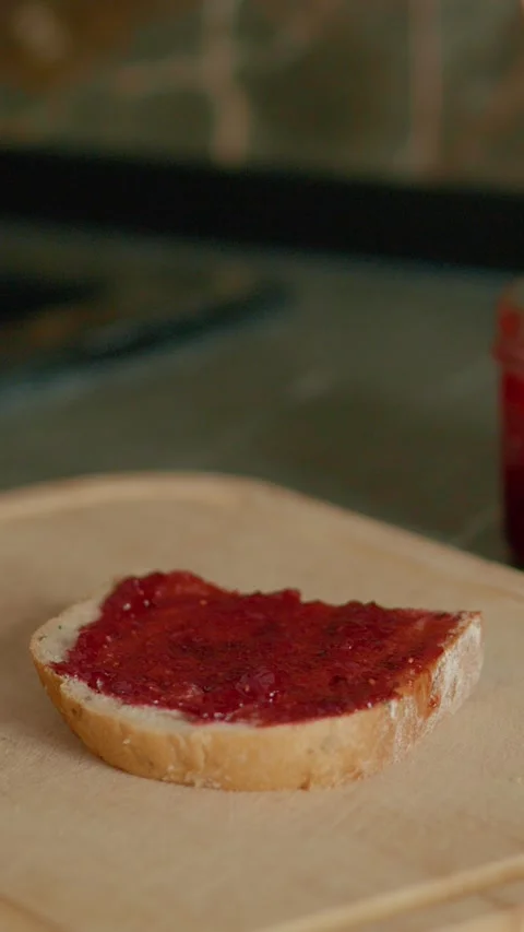 Vertical video Bread slice topped with raspberry jam on a wooden chopping board 스톡 동영상 323363748