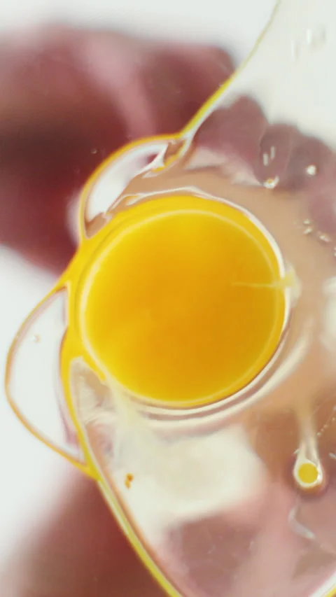 Vertical video. Breaking an egg into a transparent bowl. Stock Footage 345059155
