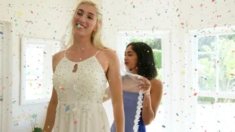 Vertical video: Bride adjusting hair and veil, friend arranging garland in room, Stock Footage 331158357