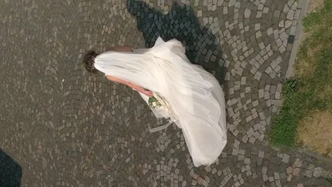 Vertical video. The bride walks on the old cobblestones. Aerial view. Stock-Footage 267589190