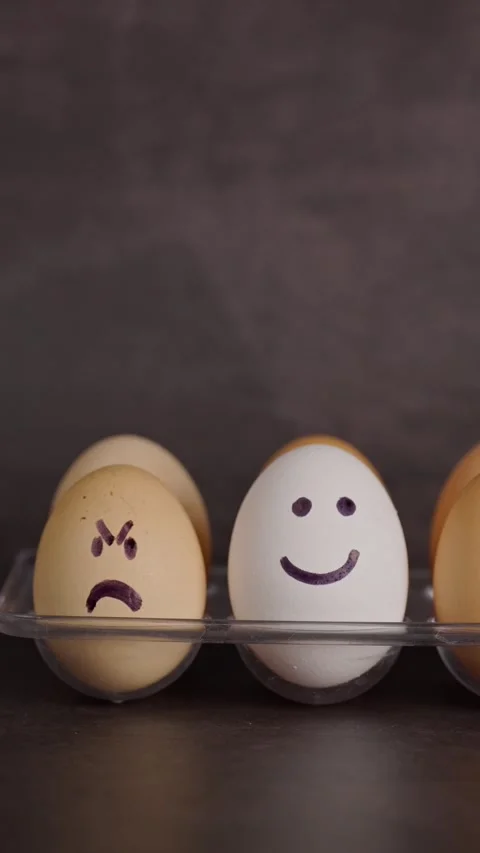 Vertical video, brown egg with a sad and angry face and white egg Stock Footage 281372760