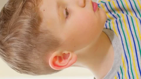 Vertical video. A brown-haired boy eats natural salad leaves with pleasure Stock Footage 250454390