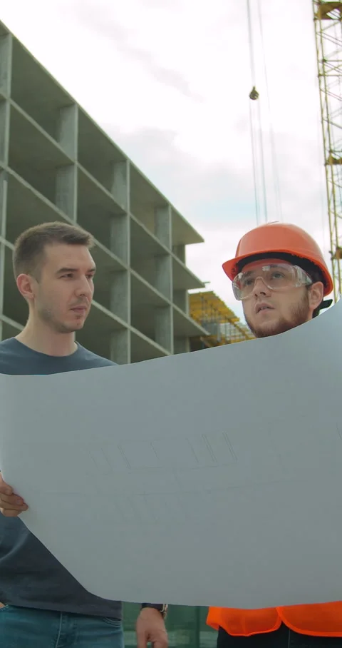 Vertical video. Builder with a male client near building under construction Stock Footage 345504172