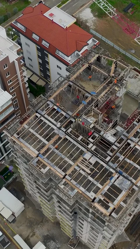 Vertical Video of Builders Working on Tall Structure With Crane Stock Footage 342423920