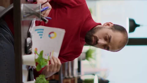 Vertical video: Business man comparing financial charts on files and computer Stock Footage 171930820