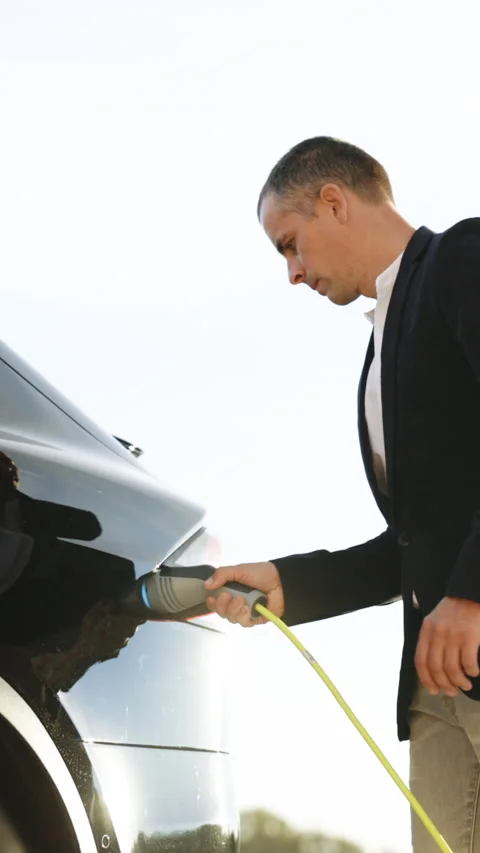Vertical Video of Businessman plugging in charging cable to to electric vehicle Stock Footage 305542484