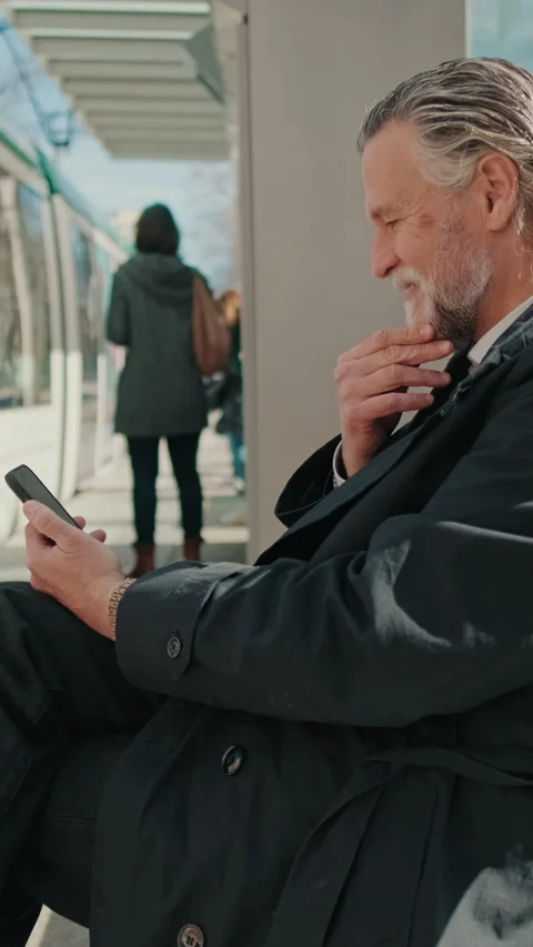 Vertical video, Businessman Using Phone at Tram Stop Stock Footage 312184365