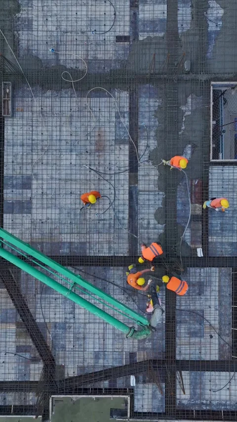 Vertical Video: Bustling construction site with workers pouring concrete for a Stock Footage 297642690