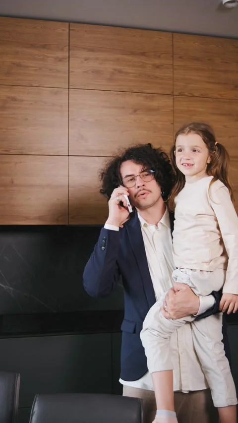 Vertical video A busy father multitasks by holding a professional phone call in Stock Footage 296824594