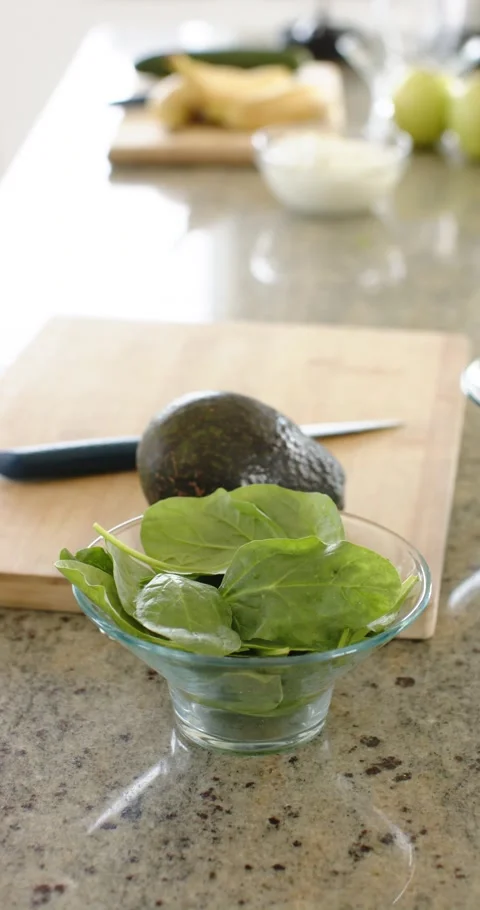 Vertical video: Camera is holding focus on glass bowl of greens on stone Stock Footage 345217861