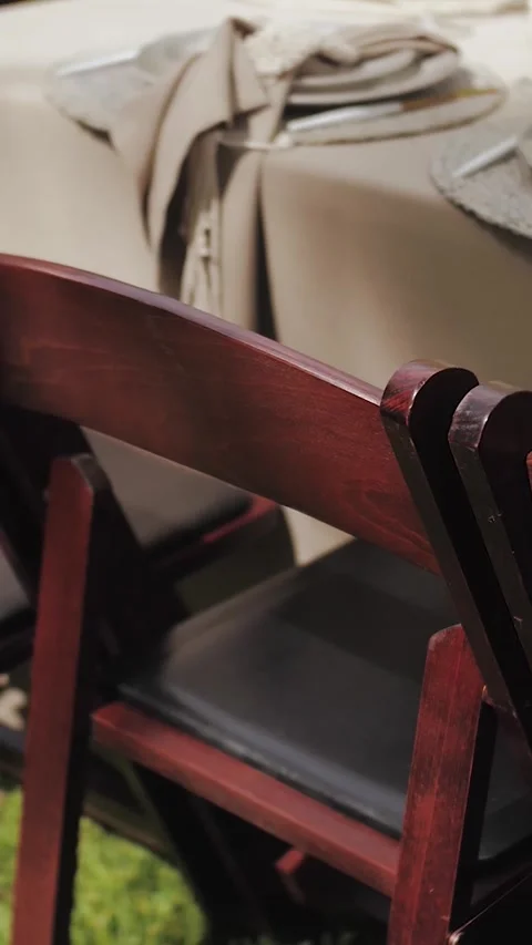 Vertical video. The camera moves along the backs of wooden chairs. Outdoor Stock Footage 309099361