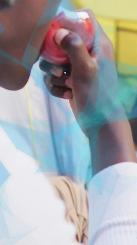 Vertical video: Camera panning, boy reaching red apple, taking bites while blue Stock Footage 334550580
