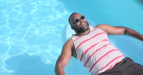 Vertical video: Camera panning, man bracing on float fixing shades in home pool, Stock Footage 335365991