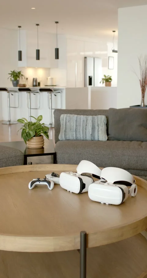Vertical video: Camera is panning to three VR headsets and white gamepad on Stockbeeldmateriaal 345129425