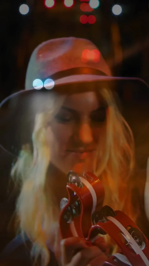 Vertical video: Camera pulling close, female performer shaking red tambourine, Stock Footage 332594710
