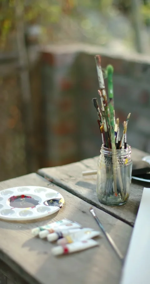 Vertical video: Camera pulling focus toward jar of brushes on wooden table Stock Footage 345323597