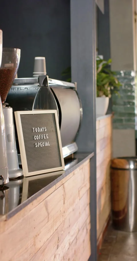 Vertical video: Camera sliding right, revealing letterboard by espresso machine, Stock Footage 345396059