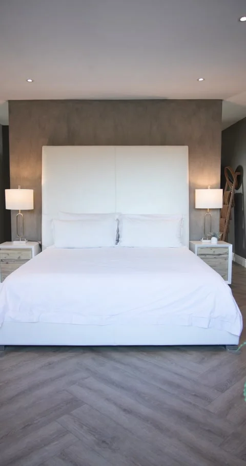 Vertical video: Camera starting panning left in bedroom revealing white bed and Stock Footage 345491269