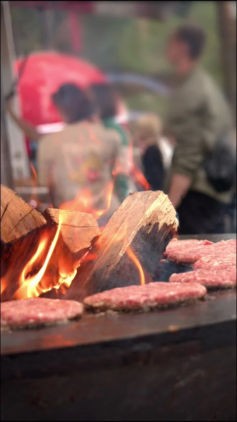 Vertical video captures process of cooking juicy burger patties at street Video stock 346408376