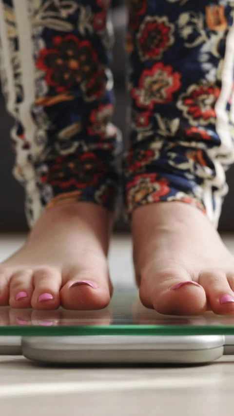 Vertical Video of checking BMI weight loss. Girl barefoot measuring body fat Stock Footage 305449416