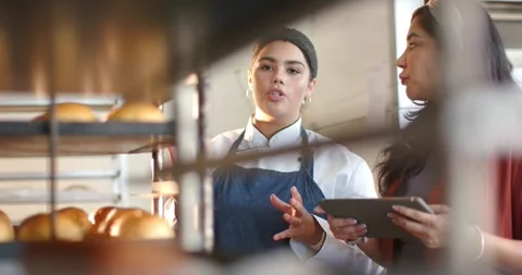 Vertical video: Chef in coat talking at rack of rolls in bakery, peer tapping Video stock 342494529