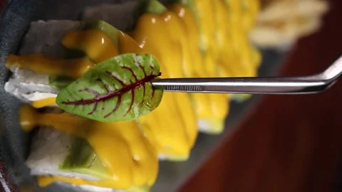 Vertical video the chef decorates the rolls with a green leaf japan kitchen Stock Footage 176390687