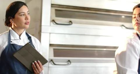 Vertical video: Chef pointing at tray while holding tablet guiding baker shaping Stock Footage 344105645