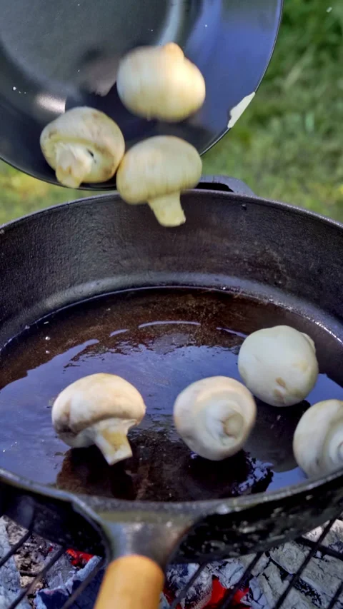 Vertical video. Chef pours champignon mushrooms into a cast iron pan. Grilling. Stock Footage 315269321